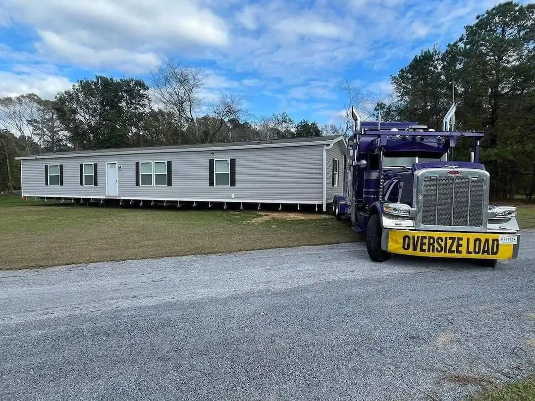 Mobile home moving services — professional manufactured home transport on a Peterbilt with oversize-load escort